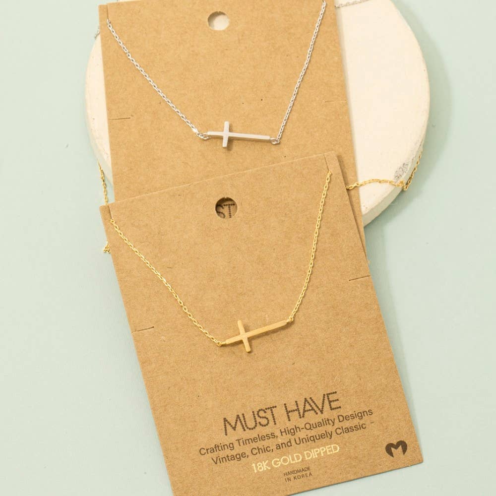 Necklace with a cross pendant on a 'Must Have' branded card against a light green background