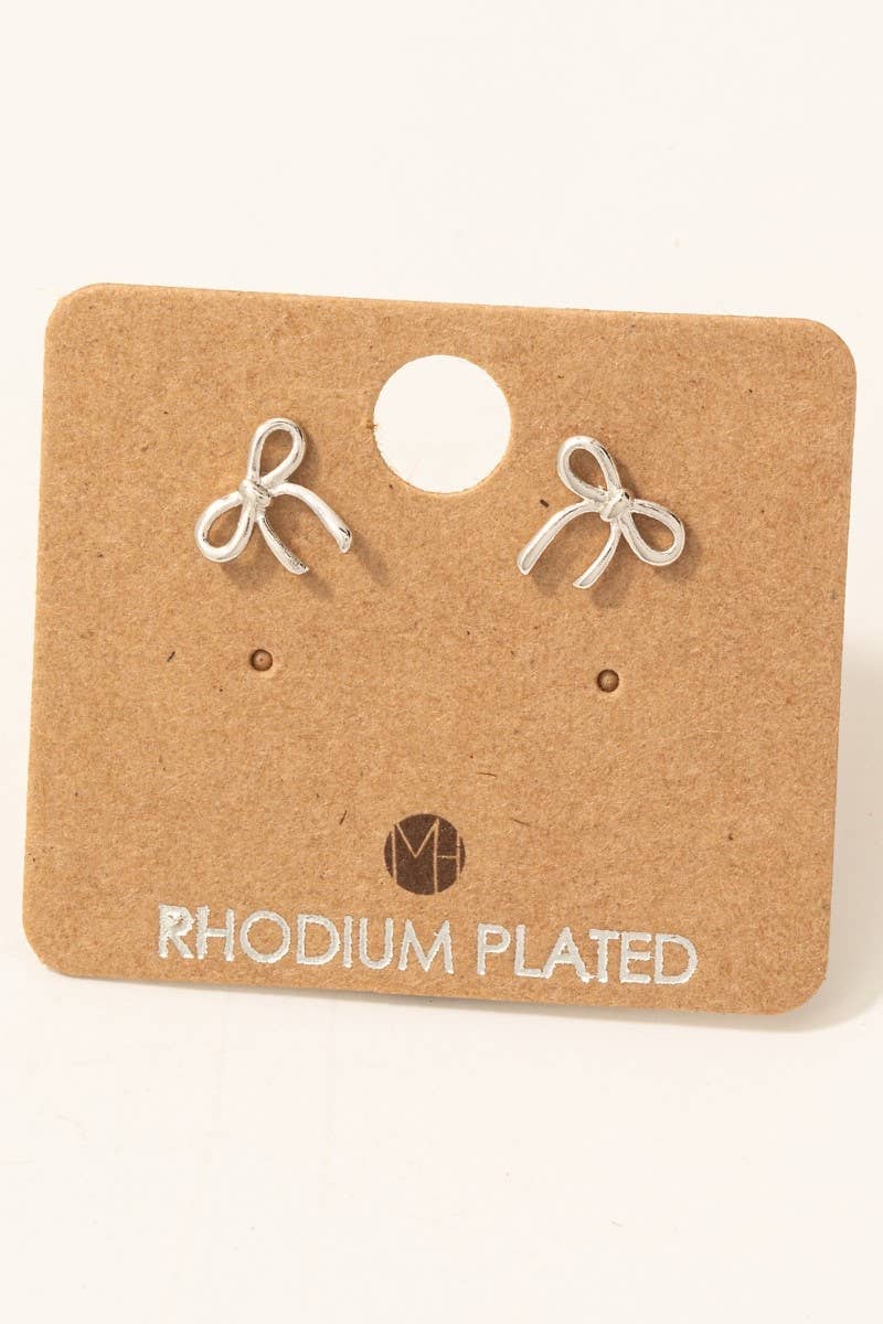 Pair of rhodium-plated bow-shaped earrings on a cardboard card with 'M' logo.