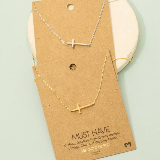 Necklace with a cross pendant on a 'Must Have' branded card against a light green background