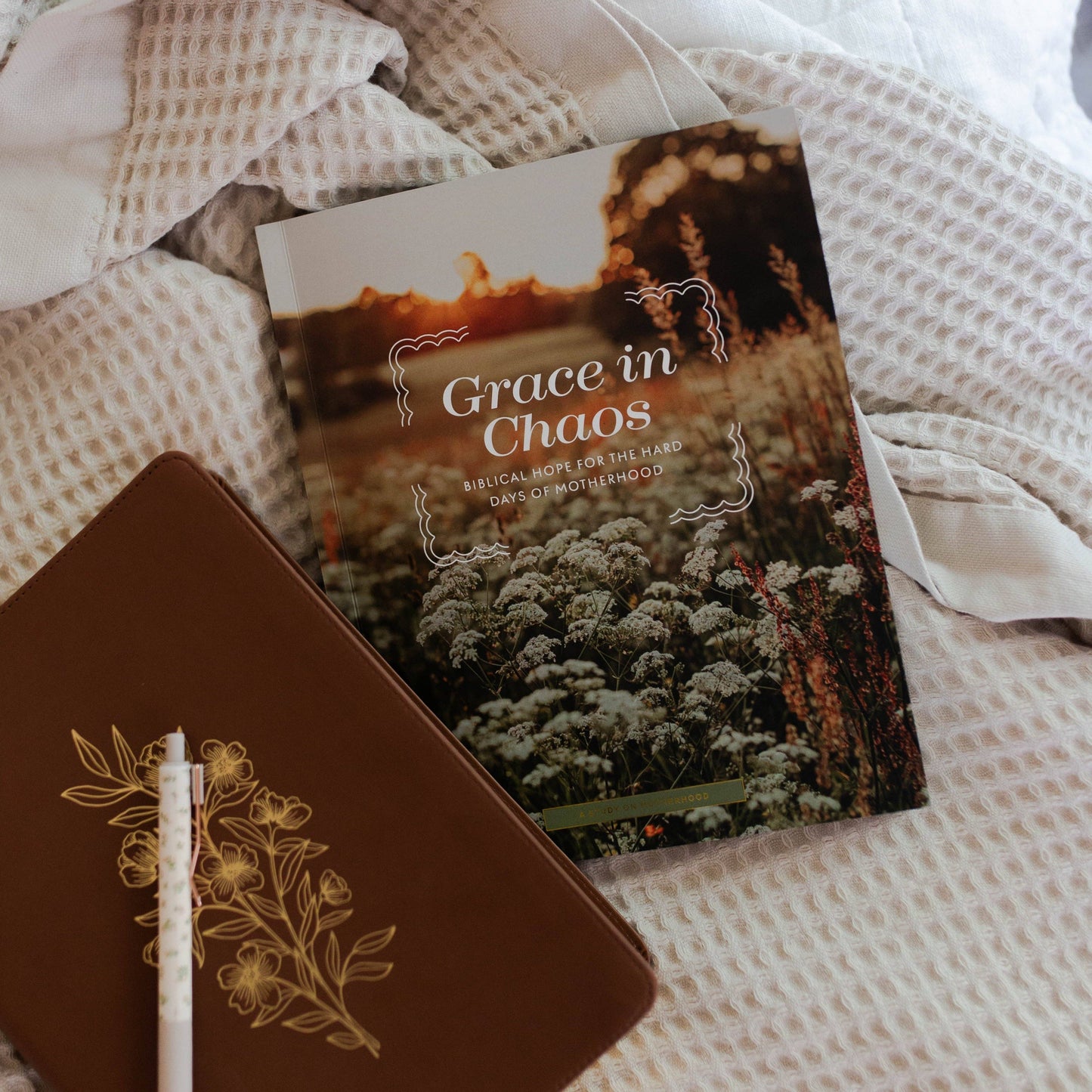 Book titled 'Grace in Chaos' on a textured surface with a pen.