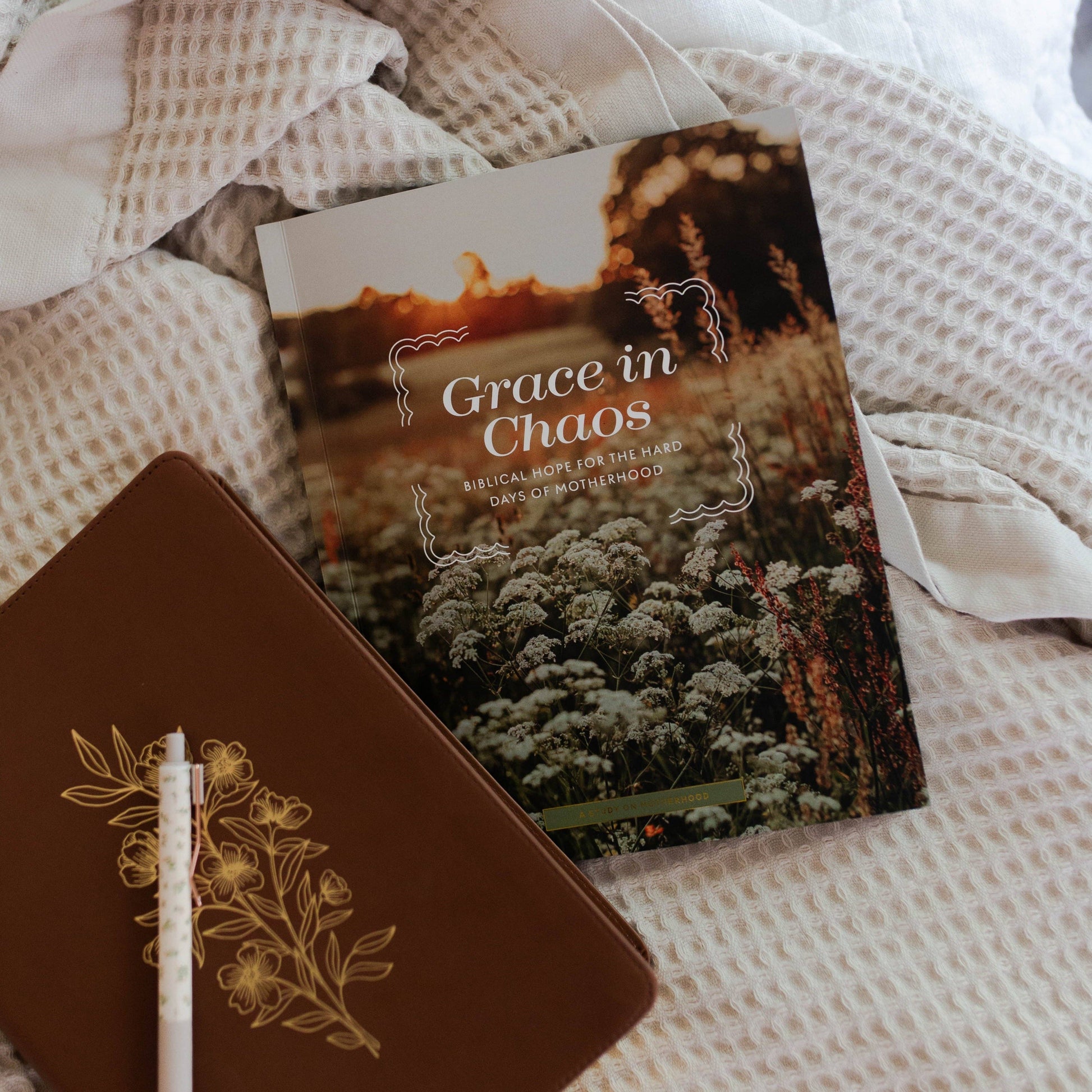Book titled 'Grace in Chaos' on a textured surface with a pen.