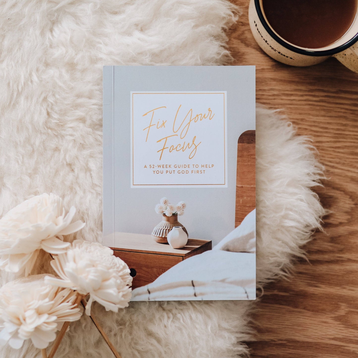 Book titled 'Fix Your Focus' on a wooden surface with flowers and a mug.