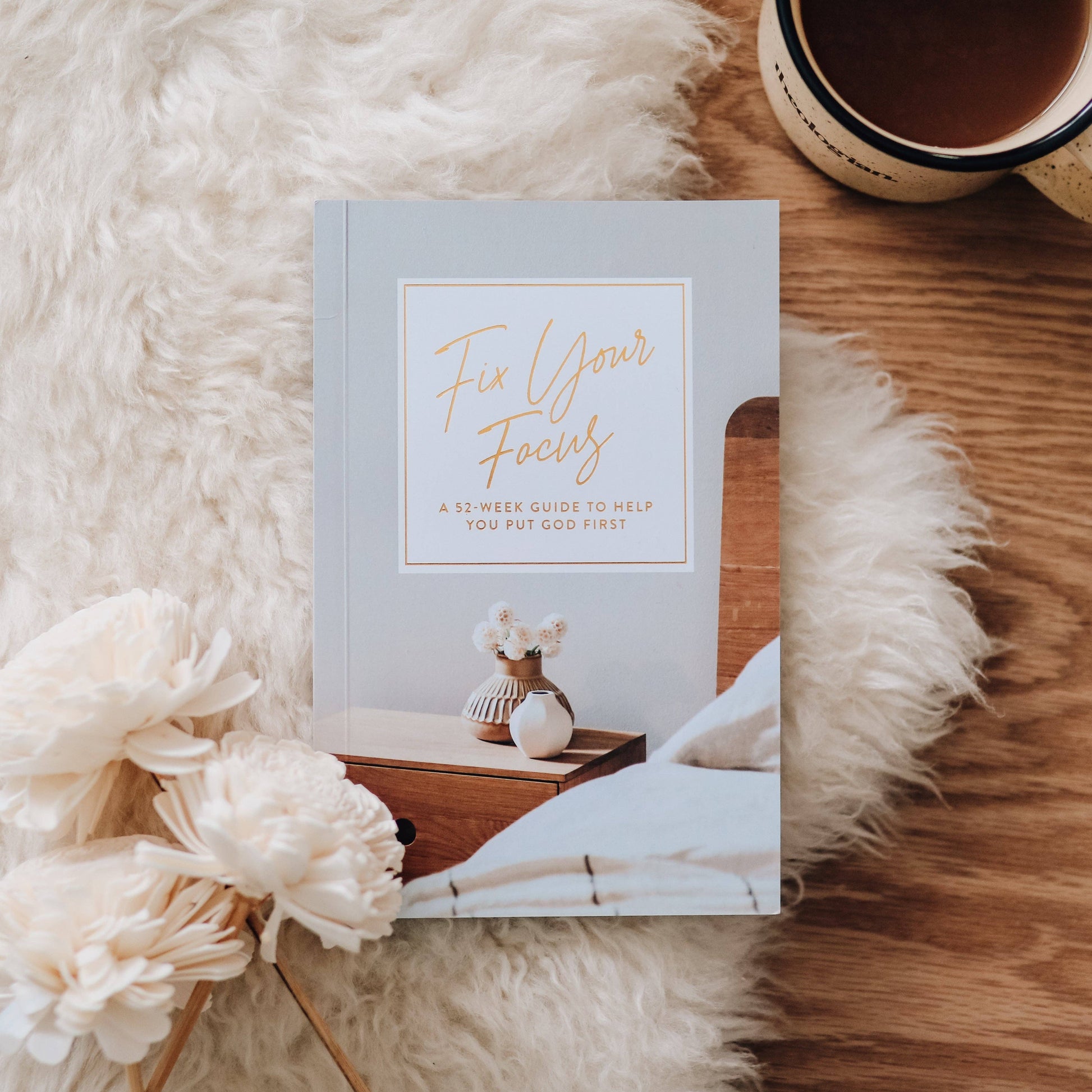 Book titled 'Fix Your Focus' on a wooden surface with flowers and a mug.