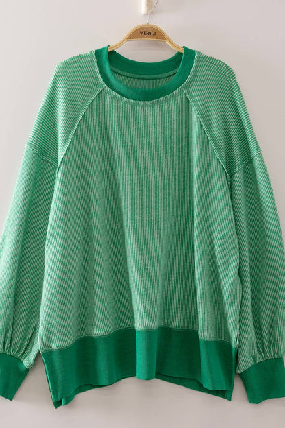 Green sweater on a hanger against a white background