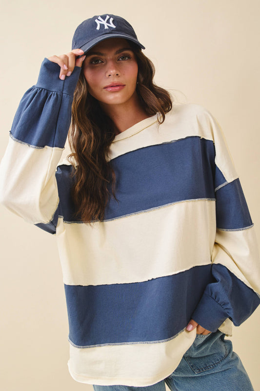 Woman wearing a blue and white striped sweater with a cap on a beige background