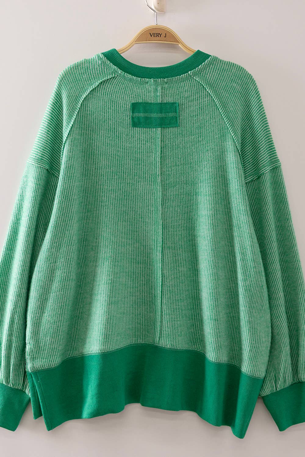 Green sweater on a hanger against a white background