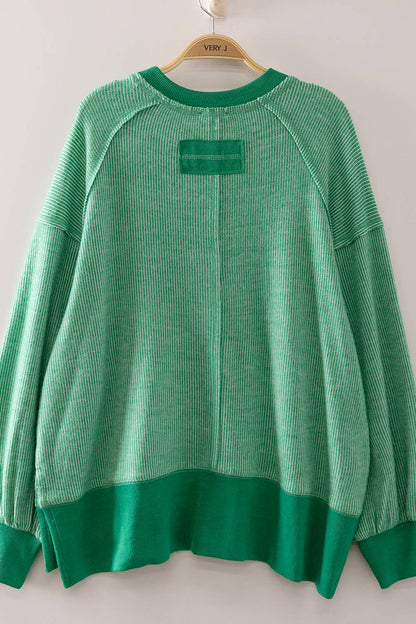 Green sweater on a hanger against a white background