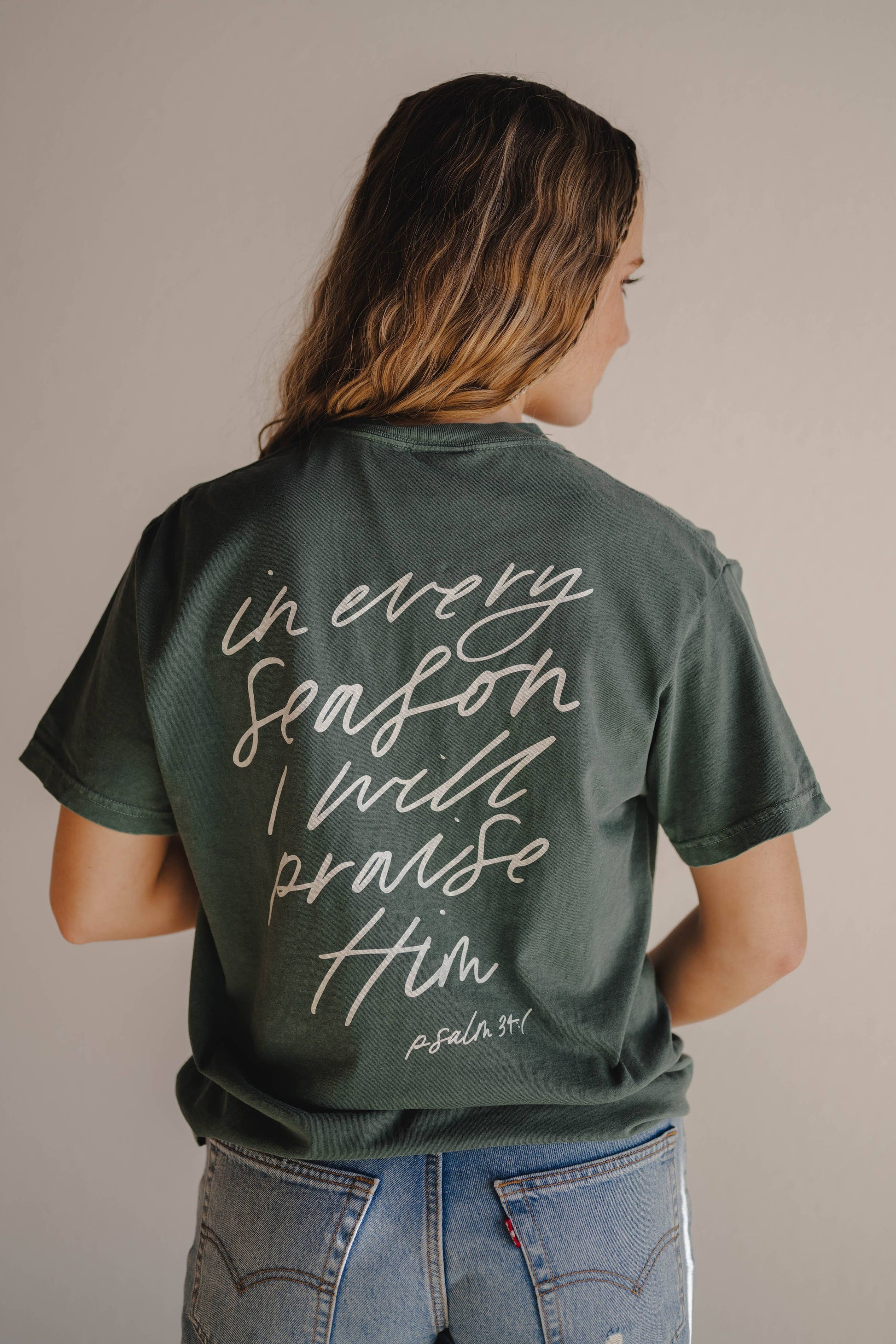 Person wearing a green t-shirt with a motivational quote on the back against a neutral background