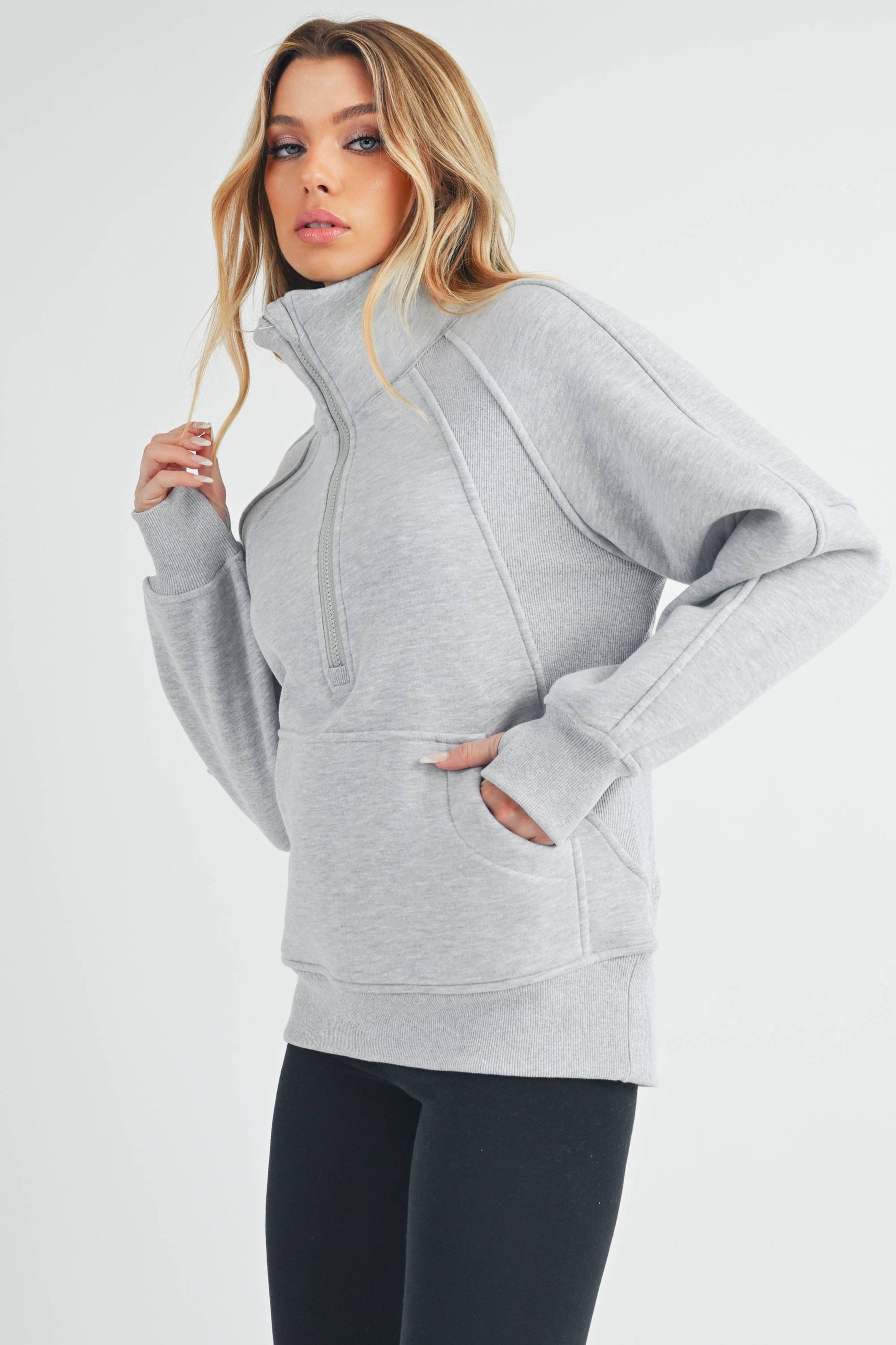 Woman wearing a gray zip-up hoodie on a white background