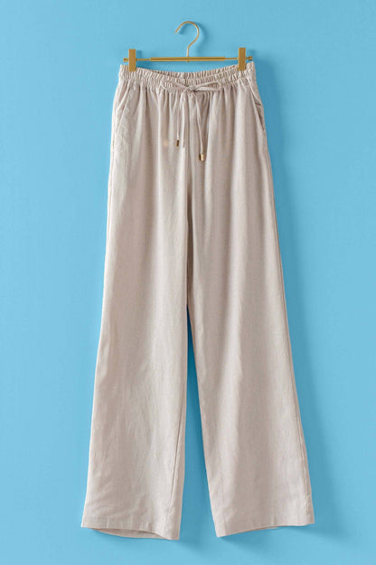 Beige pants hanging on a wooden hanger against a blue background