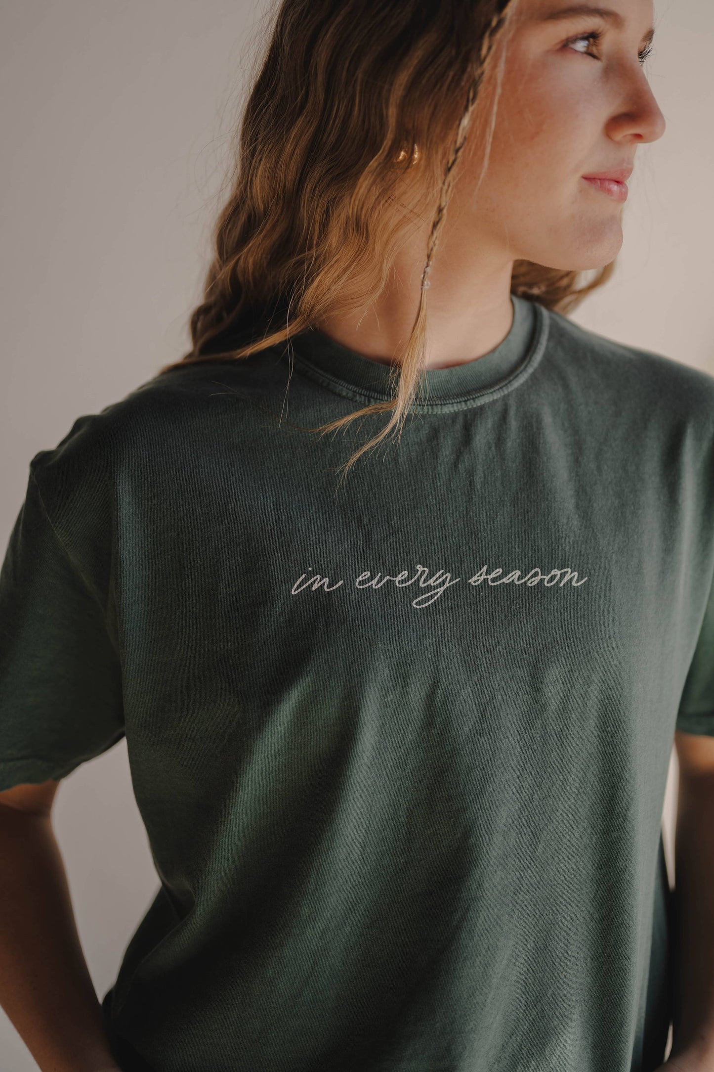 Person wearing a green t-shirt with 'in every season' text.