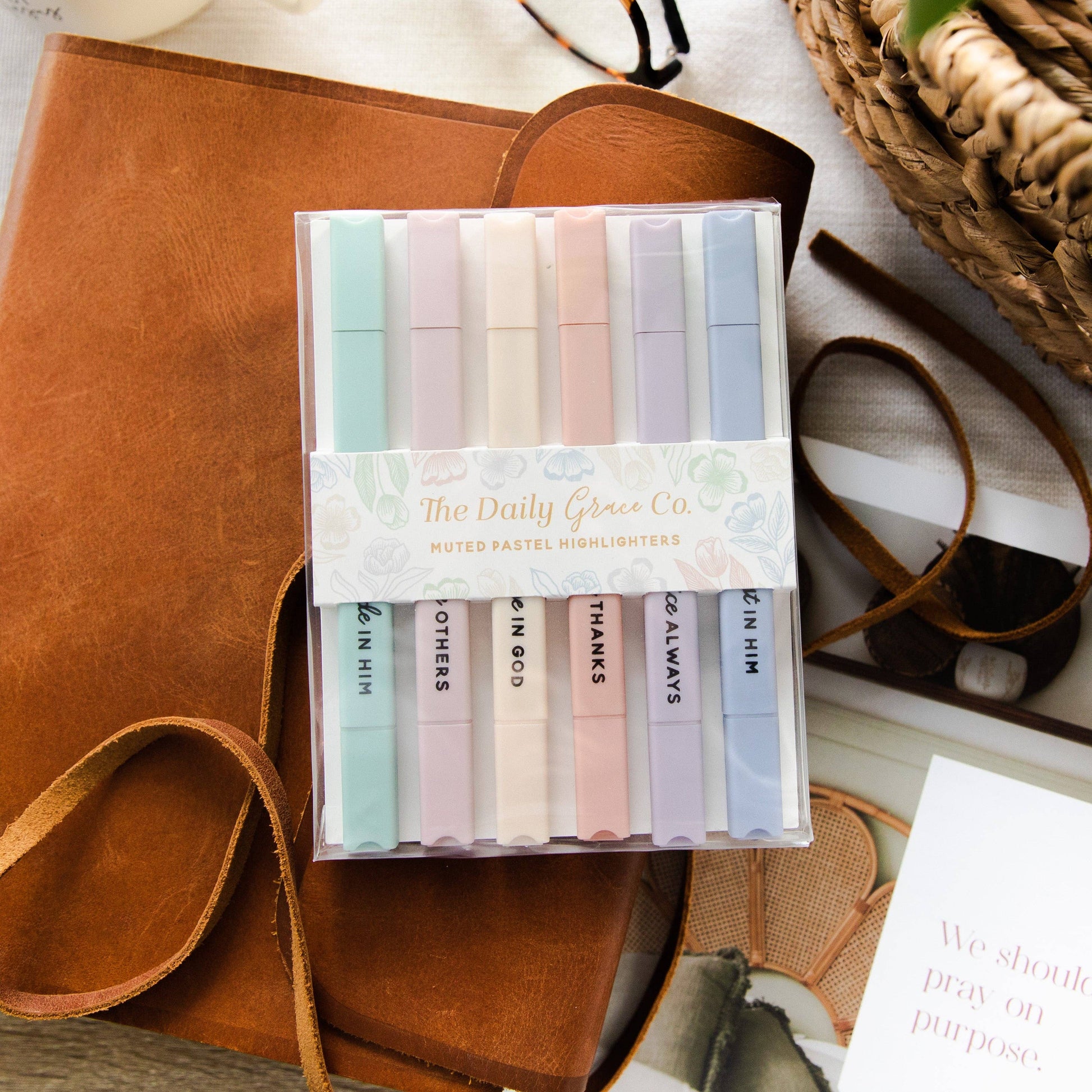 Set of colorful markers in a clear plastic case on a brown leather surface.