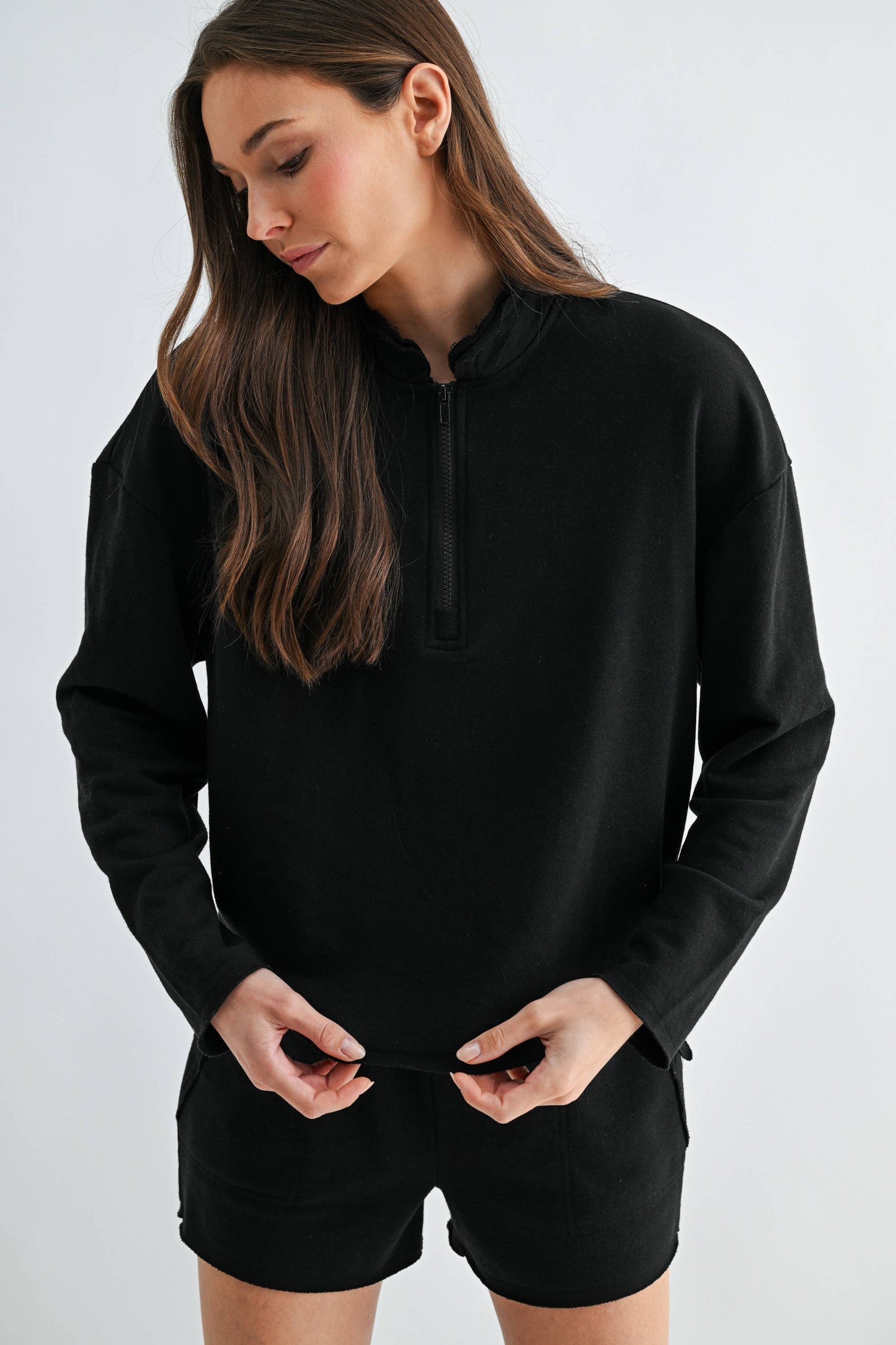 Woman wearing a black hoodie and shorts on a white background