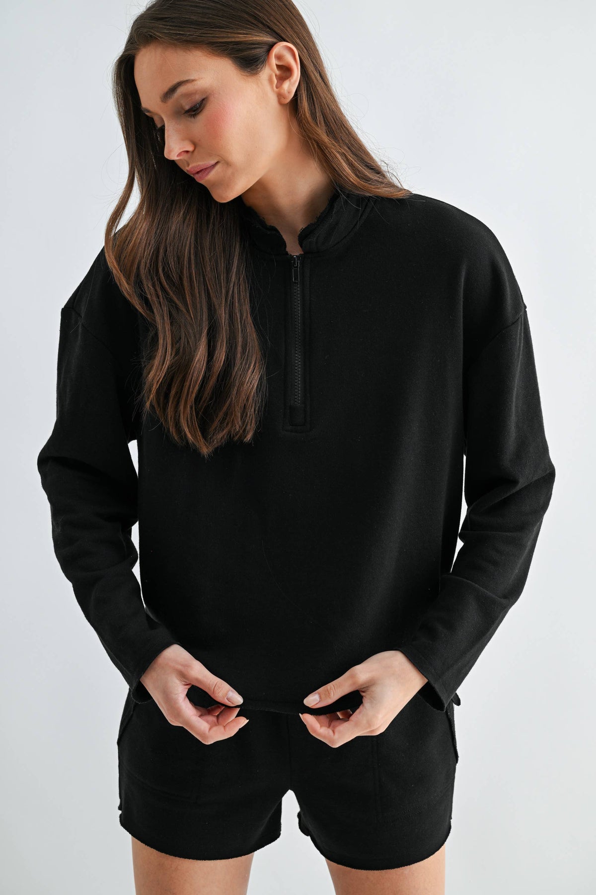 Woman wearing a black hoodie and shorts on a white background