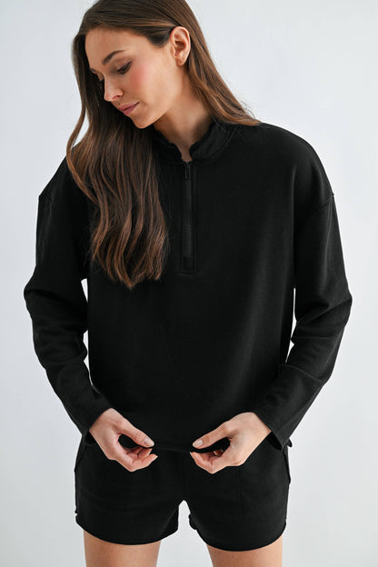 Woman wearing a black hoodie and shorts on a white background