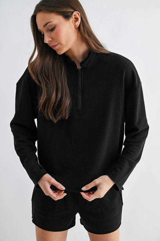 Woman wearing a black hoodie and shorts on a white background