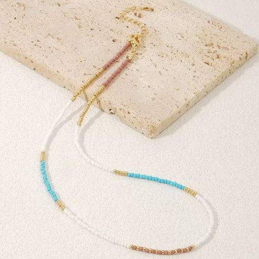 Beaded necklace with gold accents on a stone surface