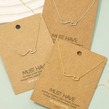Gold and silver necklaces on brown 'Must Have' branded cards against a light green background.