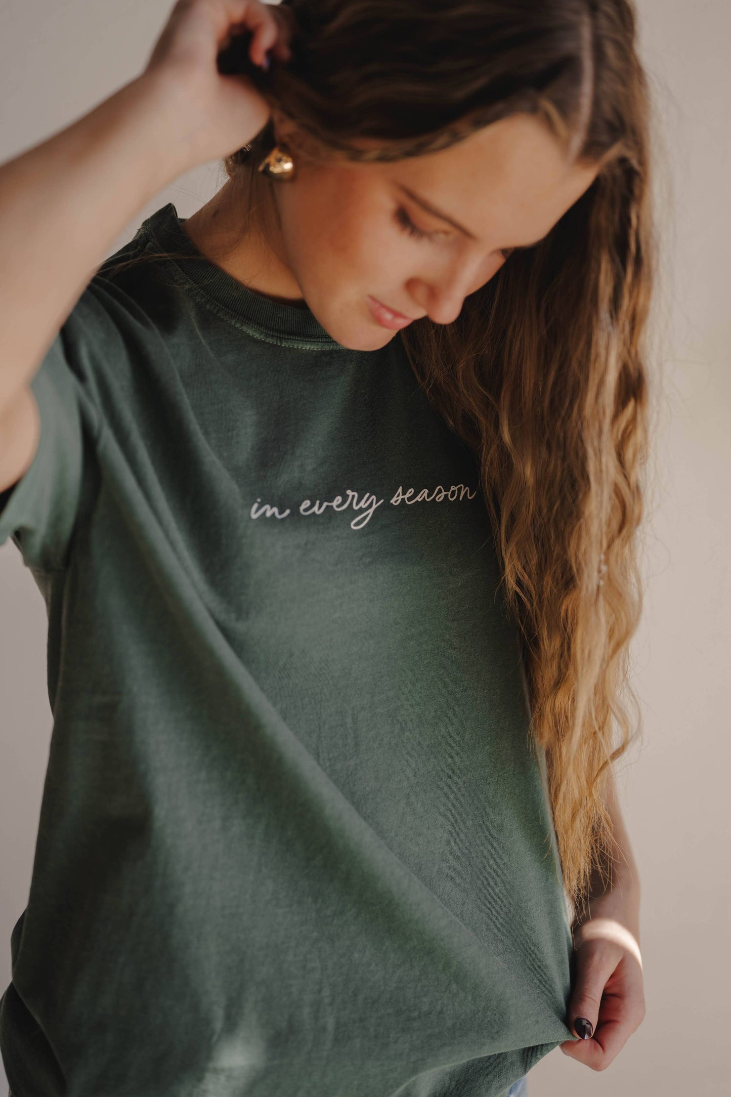 Woman wearing a green t-shirt with text, looking down.