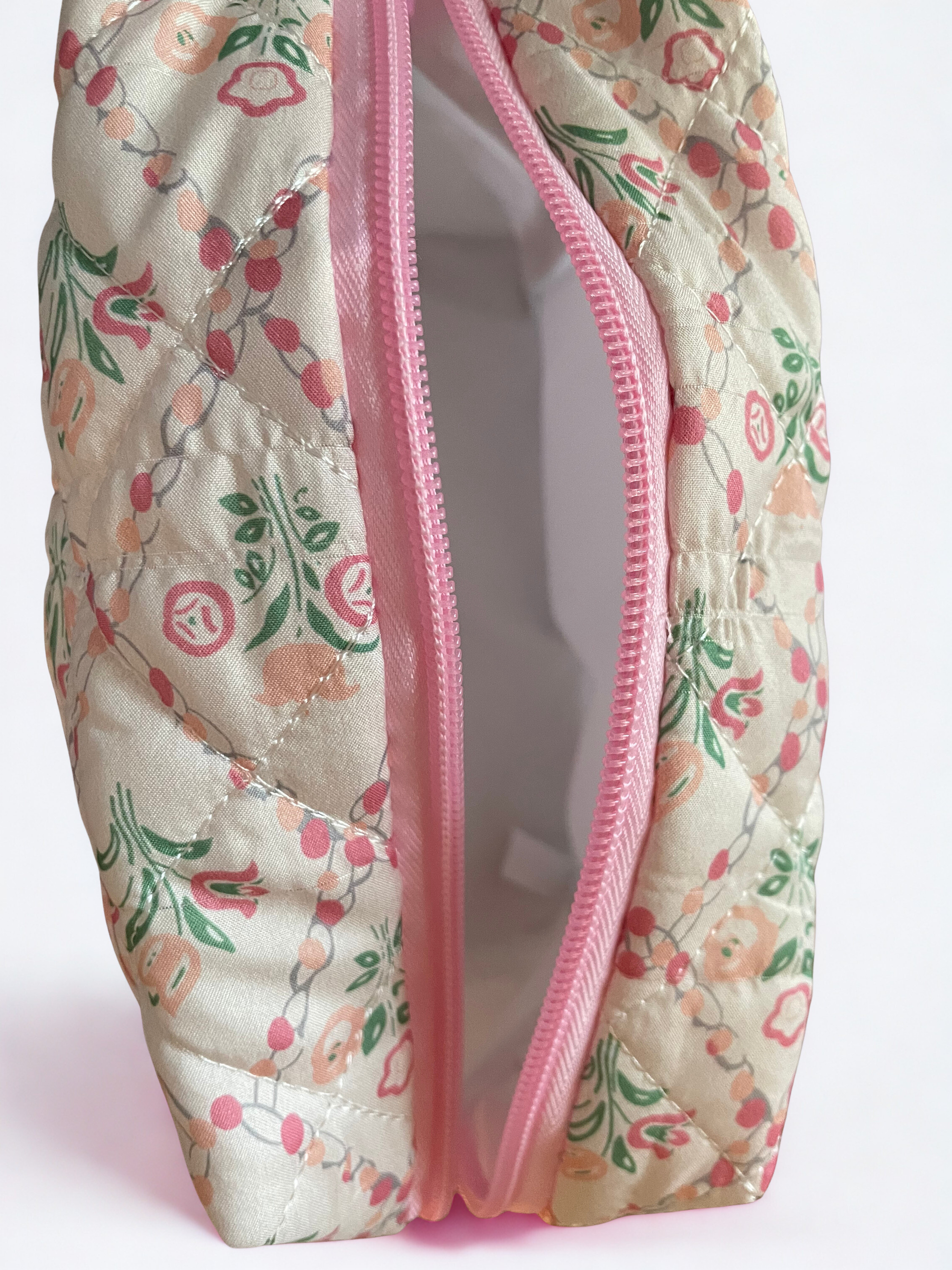 Floral-patterned pouch with a pink zipper on a light pink background