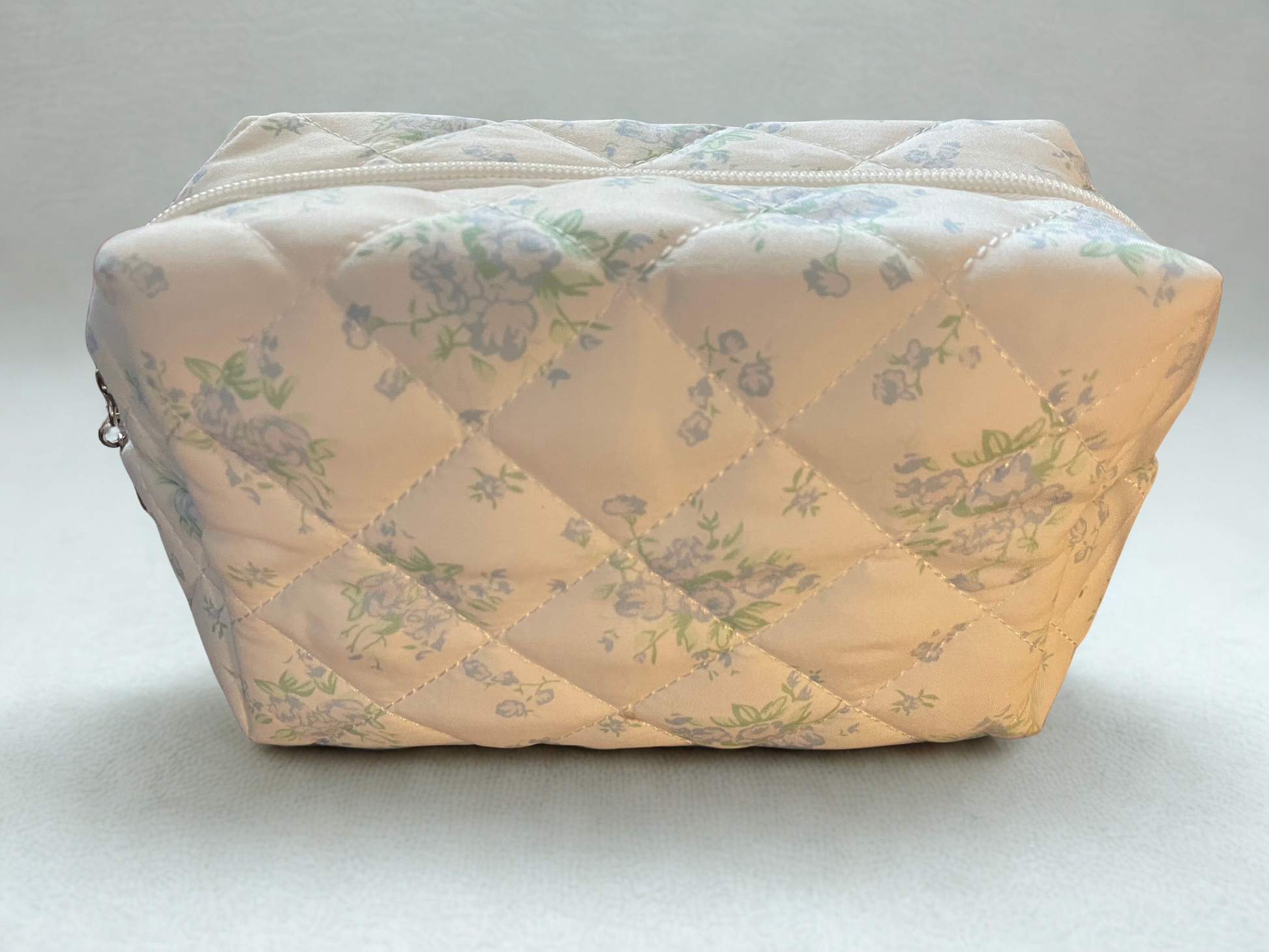 Quilted fabric pouch with floral pattern on a light gray background