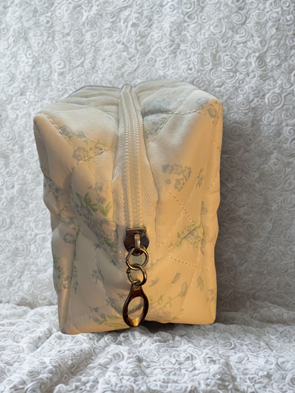 Floral-patterned pouch with a zipper and keychain on a textured gray background