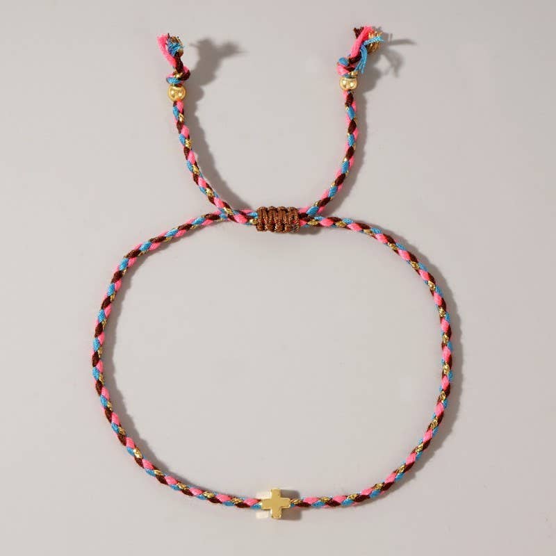 Colorful braided bracelet with a small gold cross on a light gray background