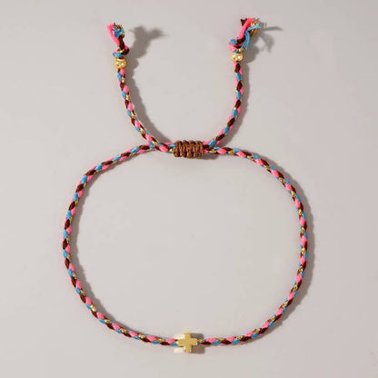 Colorful braided bracelet with a small gold cross on a light gray background