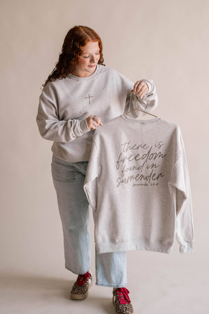 Person holding a t-shirt with text on a hanger against a plain background