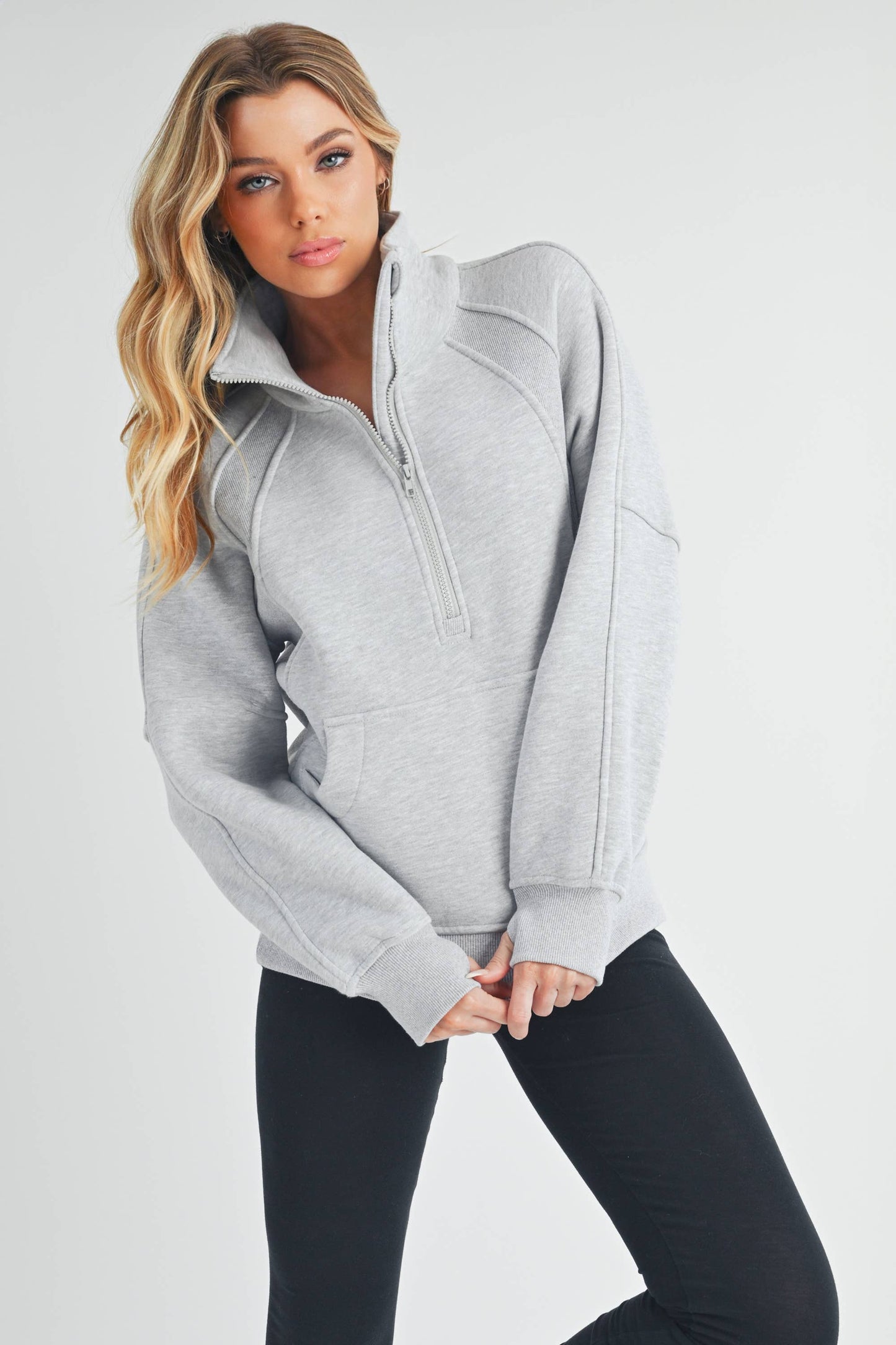 Woman wearing a gray zip-up jacket on a white background