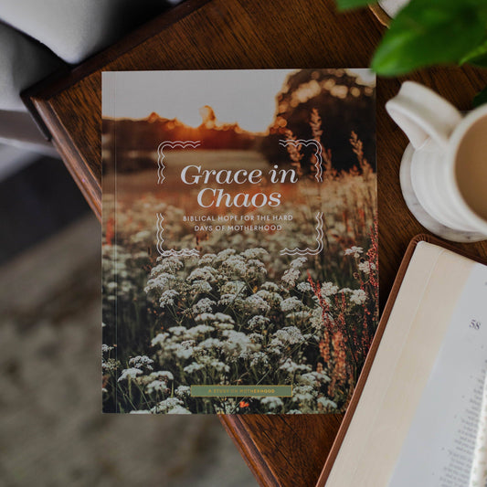 Book titled 'Grace in Chaos' on a wooden surface with a cup of coffee and book in the background.