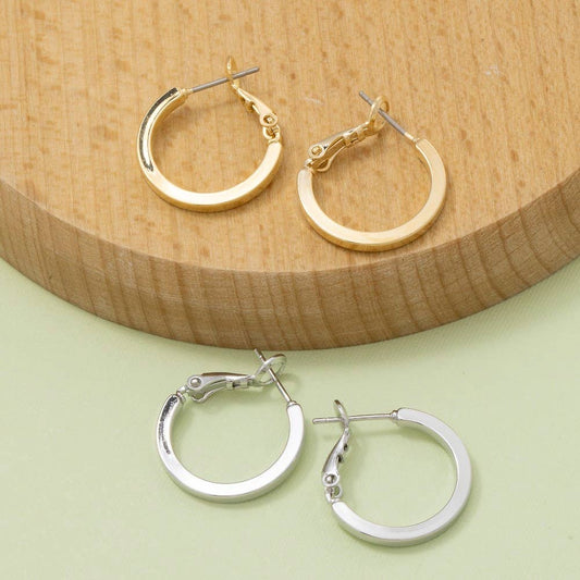 Gold and silver hoop earrings on a wooden and green background