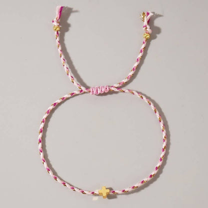 Pink and gold braided bracelet on a gray background