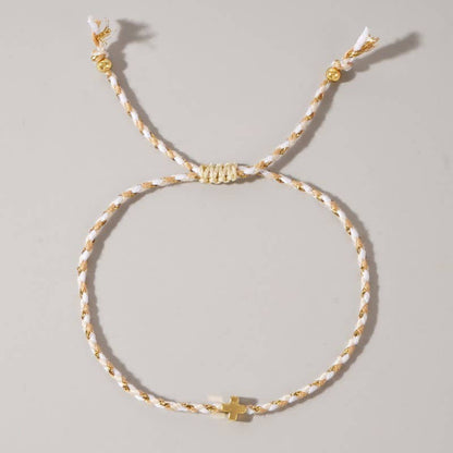 Bracelet with gold and white cord on a light gray background