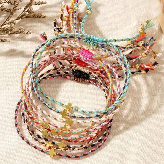 Multicolored braided bracelets with small charms on a light background