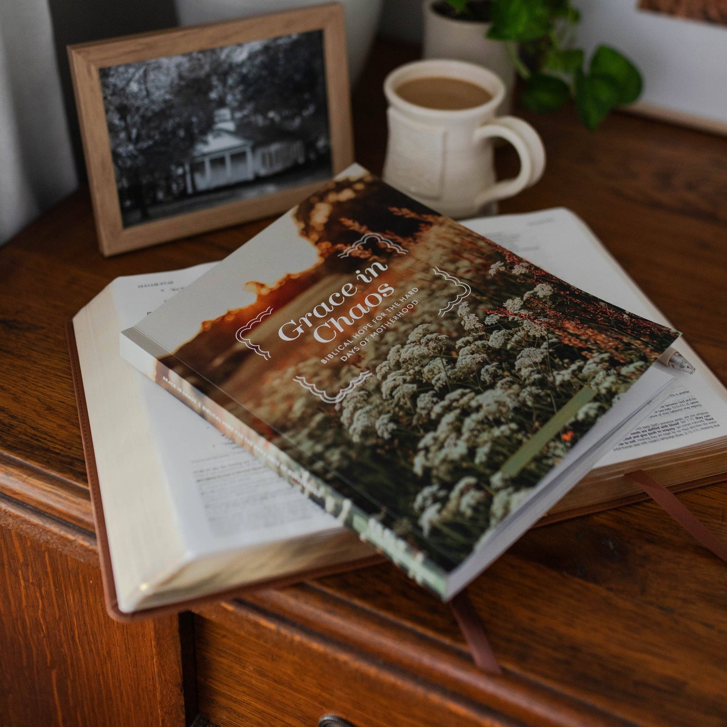 Book titled 'Grace in Chaos' on a wooden surface with a mug and photo frame in the background.