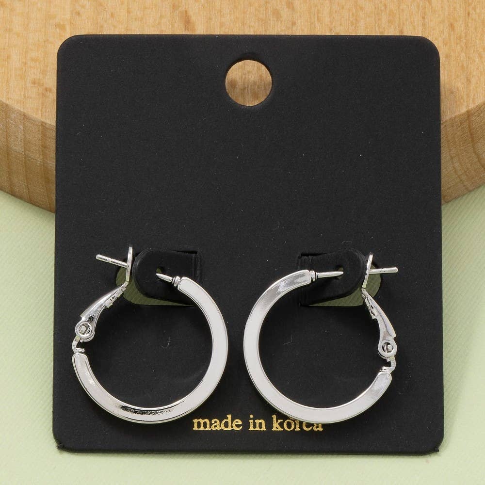 Silver hoop earrings on a black card with 'made in Korea' text, against a wooden background.