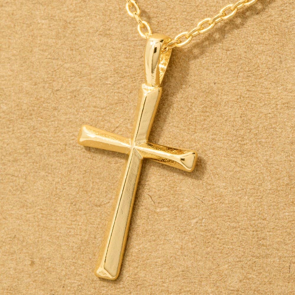 Gold cross pendant on a gold chain against a beige background