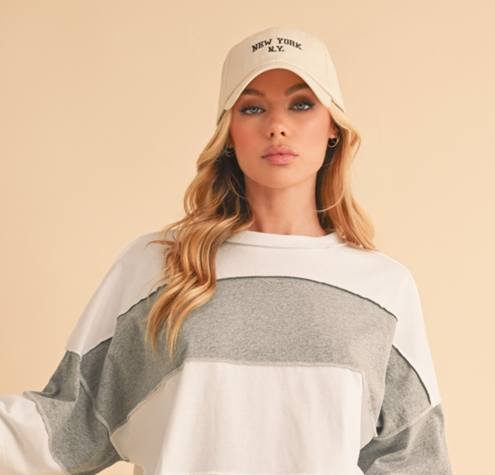 Woman wearing a cap and a color-blocked sweater on a beige background